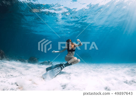 Freediver young woman with fins swim over sand Freediver young woman with fins swim over sand 49897643