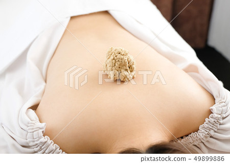 A large bowl placed on the back of a woman in a bright acupuncture 49899886