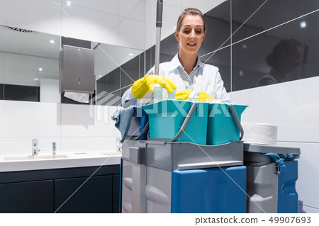 Janitor or charlady with her work tools looking at camera in toilet 49907693