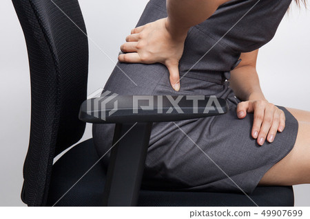 Young businesswoman having back pain while sitting Young businesswoman having back pain while sitting 49907699