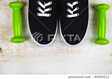 Sneakers and dumbbells a on a wooden background Sneakers and dumbbells a on a wooden background 49909812