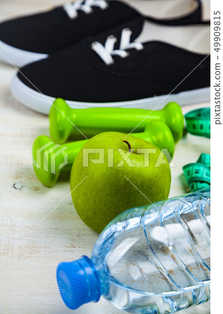 Gym shoes, dumbbells, a bottle of water, an apple 49909815