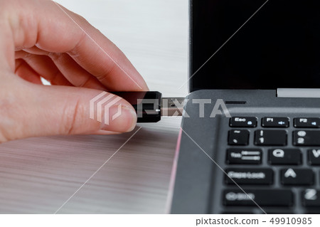 Female hand inserting USB flash drive and laptop 49910985