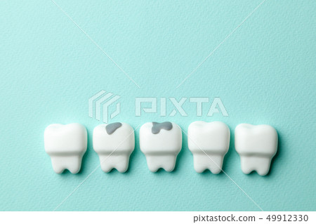 Healthy white teeth and tooth with caries on green mint background. Copy space for text. 49912330