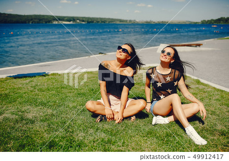 Stylish girls walking in a summer park Stylish girls walking in a summer park 49912417