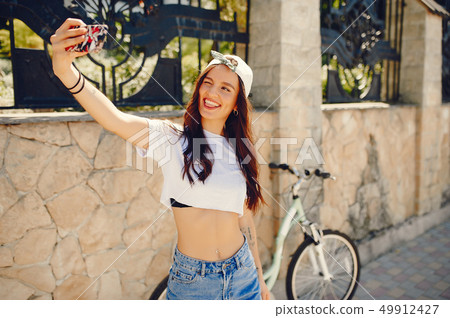Stylish girl standing in a summer city Stylish girl standing in a summer city 49912427