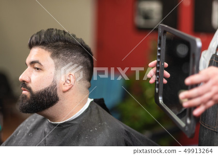 Handsome bearded man looking in the mirror after haircut., at barber shop. Handsome bearded man looking in the mirror after haircut., at barber shop. 49913264