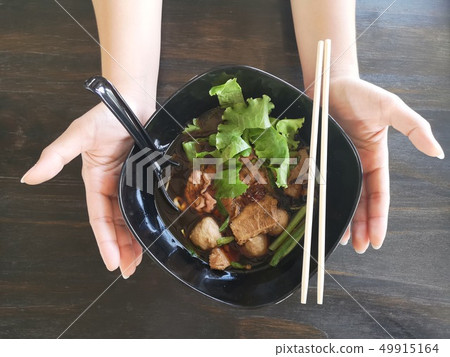 Two hands hold the black bowl of Rice noodles soup 49915164