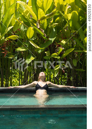 Sensual young woman relaxing in outdoor spa infinity swimming pool surrounded with lush tropical Sensual young woman relaxing in outdoor spa infinity swimming pool surrounded with lush tropical 49920330