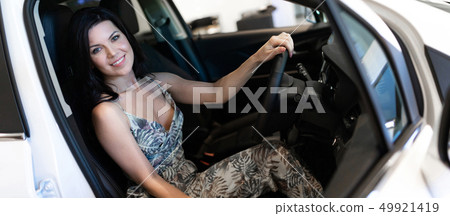 Charming customer brunet sitting in her new car just purchased in dealeship center Charming customer brunet sitting in her new car just purchased in dealeship center 49921419