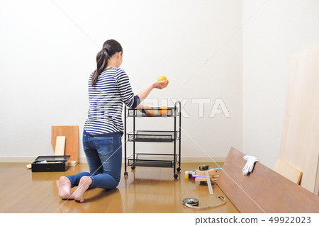 Woman assembling a kitchen rack Woman assembling a kitchen rack 49922023