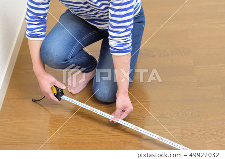 DIY A woman measuring the size of a room 49922032
