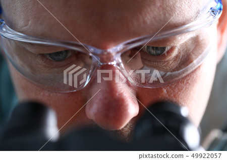 Laboratory assistant eyes looking at microscope wearing goggles Laboratory assistant eyes looking at microscope wearing goggles 49922057
