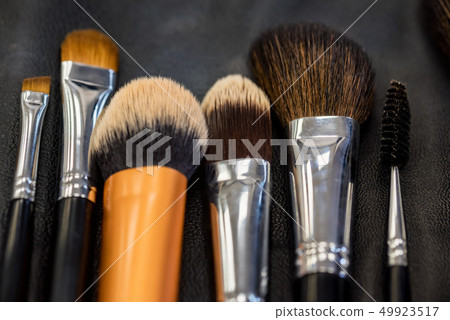 Set of makeup brushes lying on dark surface close 49923517