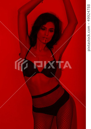 Sexy brunette in fishnet pantyhose in red light on white background Sexy brunette in fishnet pantyhose in red light on white background 49924788