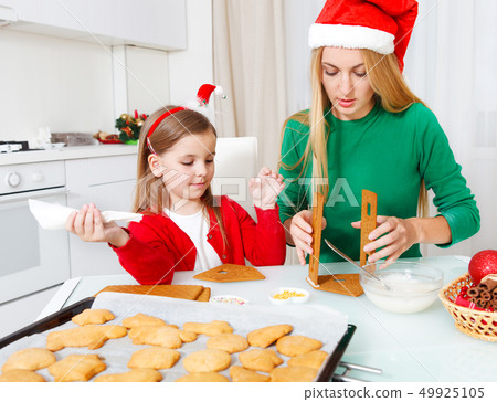 Little girl with her mother baking Christmas Little girl with her mother baking Christmas 49925105