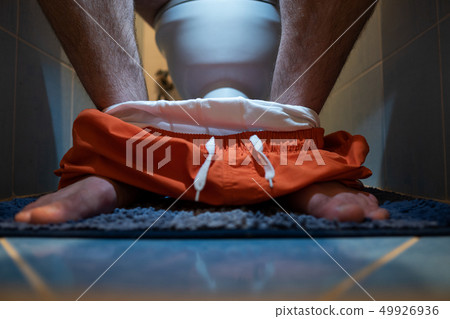 The guy is sitting on the toilet in the toilet. The guy is sitting on the toilet in the toilet. 49926936