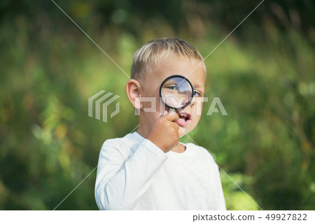 A small boy explores with a magnifying glass A small boy explores with a magnifying glass 49927822