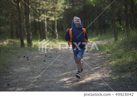 A happy little boy runs along a forest path A happy little boy runs along a forest path 49928042