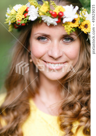 Portrait young girl in yellow dress with Flower wreath for head. Walking in park, Warm summer day. 49929035