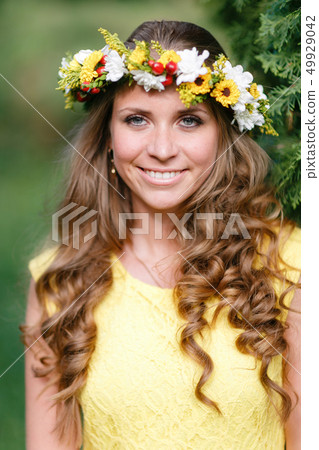 Portrait young girl in yellow dress with Flower wreath for head. Walking in park, Warm summer day. Portrait young girl in yellow dress with Flower wreath for head. Walking in park, Warm summer day. 49929042