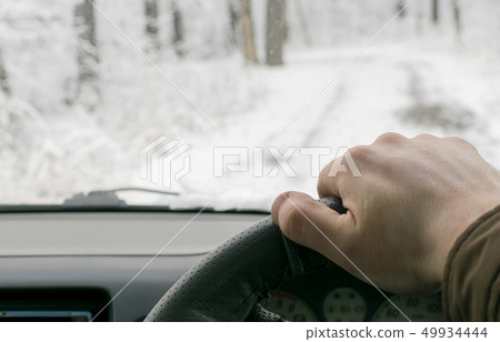 Man's hand on the steering wheel of a car Man's hand on the steering wheel of a car 49934444