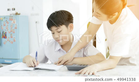 Asian mother helping her son doing homework on Asian mother helping her son doing homework on 49941338
