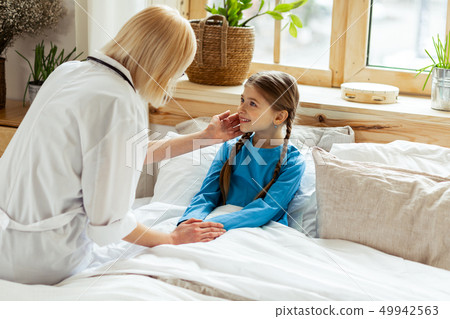 A cute girl smiling while a physician checking her temperature 49942563