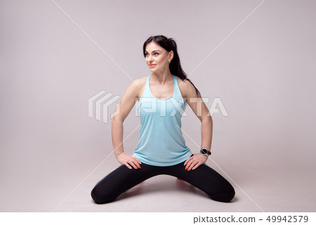Portrait of a sporty young fitness woman doing workouts isolated on gray background. 49942579