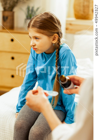 Displeased girl unwilling to take syrup suggested by a doctor Displeased girl unwilling to take syrup suggested by a doctor 49942827