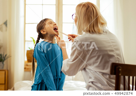 Female otolaryngologist examining throat of small cute ill girl 49942874