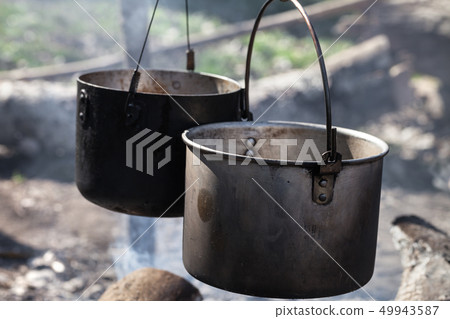 Cooking in two sooty old cauldrons on campfire at Cooking in two sooty old cauldrons on campfire at 49943587