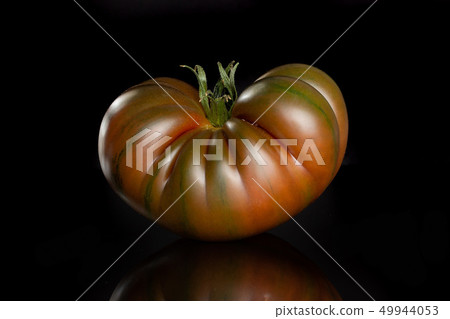 Fresh dark tomato primora isolated on black glass Fresh dark tomato primora isolated on black glass 49944053