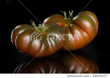 Fresh dark tomato primora isolated on black glass Fresh dark tomato primora isolated on black glass 49944077