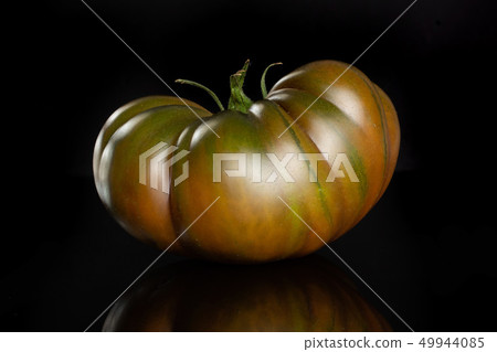 Fresh dark tomato primora isolated on black glass Fresh dark tomato primora isolated on black glass 49944085