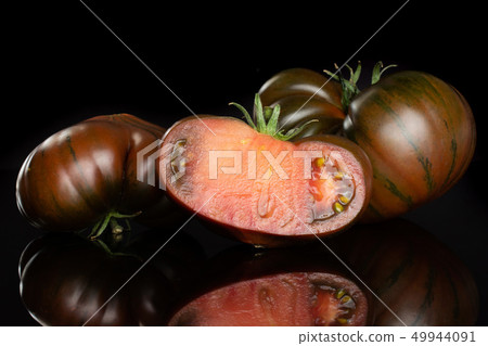 Fresh dark tomato primora isolated on black glass Fresh dark tomato primora isolated on black glass 49944091