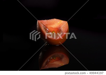 Fresh dark tomato primora isolated on black glass Fresh dark tomato primora isolated on black glass 49944197