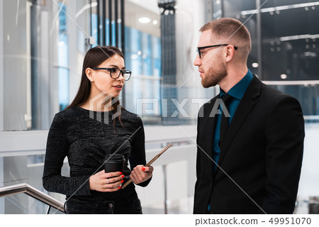 Businessman and businesswoman discussing something during the coffee break Businessman and businesswoman discussing something during the coffee break 49951070