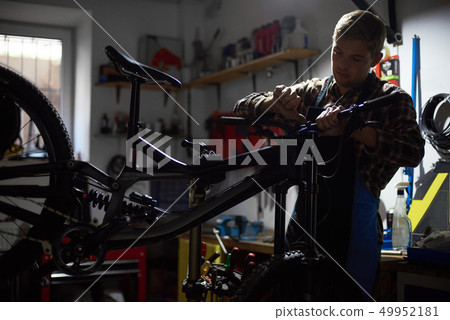 Male mechanic working in bicycle repair shop using tools Male mechanic working in bicycle repair shop using tools 49952181