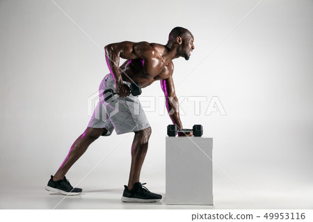 Young african-american bodybuilder training over grey background 49953116