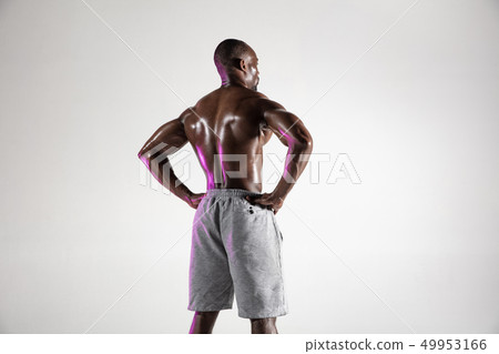 Young african-american bodybuilder training over grey background 49953166
