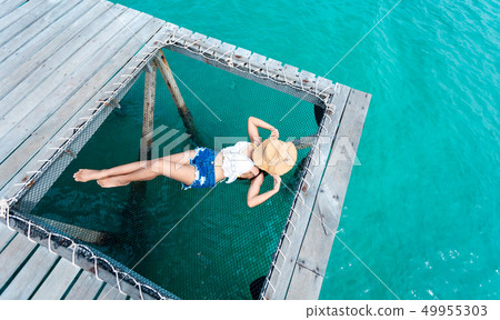 woman sleeps on a hammock at the pier near 49955303