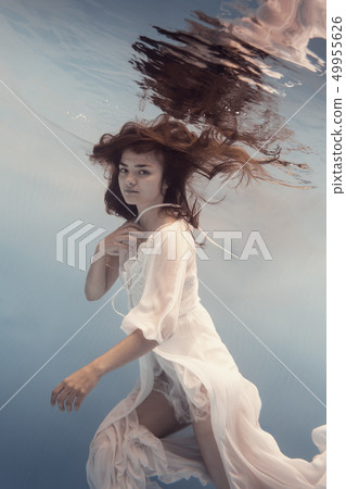 The girl in the white dress swims under water 49955626