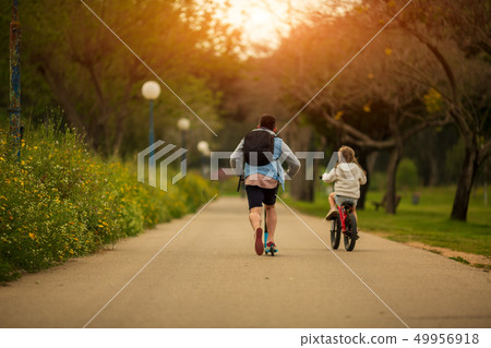 dad with daughter on bicycle and scooter dad with daughter on bicycle and scooter 49956918