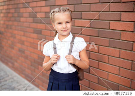Little girl with blond hair in a white shirt and blue skirt holds an empty board near the upper wall 49957139