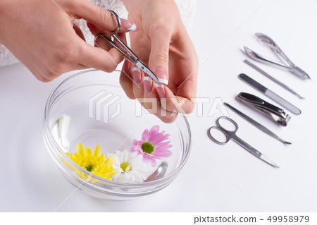 Girl cuts off the cuticle nail scissors. 49958979