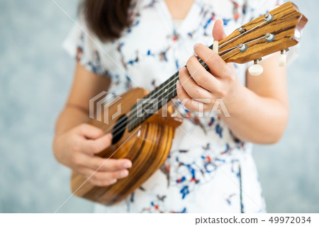 Happy woman musician playing ukulele in studio. Happy woman musician playing ukulele in studio. 49972034