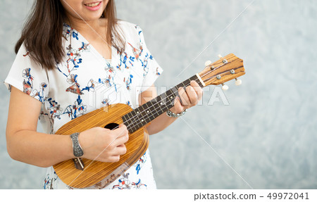 Happy woman musician playing ukulele in studio. Happy woman musician playing ukulele in studio. 49972041