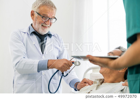 Mature doctor and senior patient in hospital ward. Mature doctor and senior patient in hospital ward. 49972070