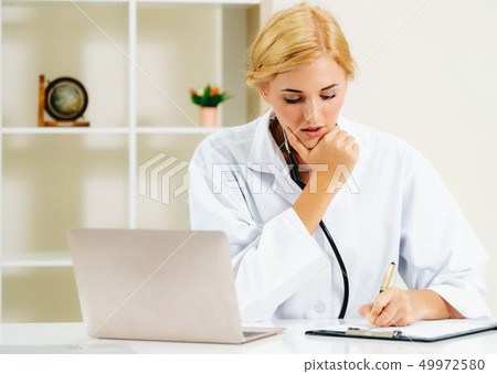 Young female doctor working in hospital office. 49972580